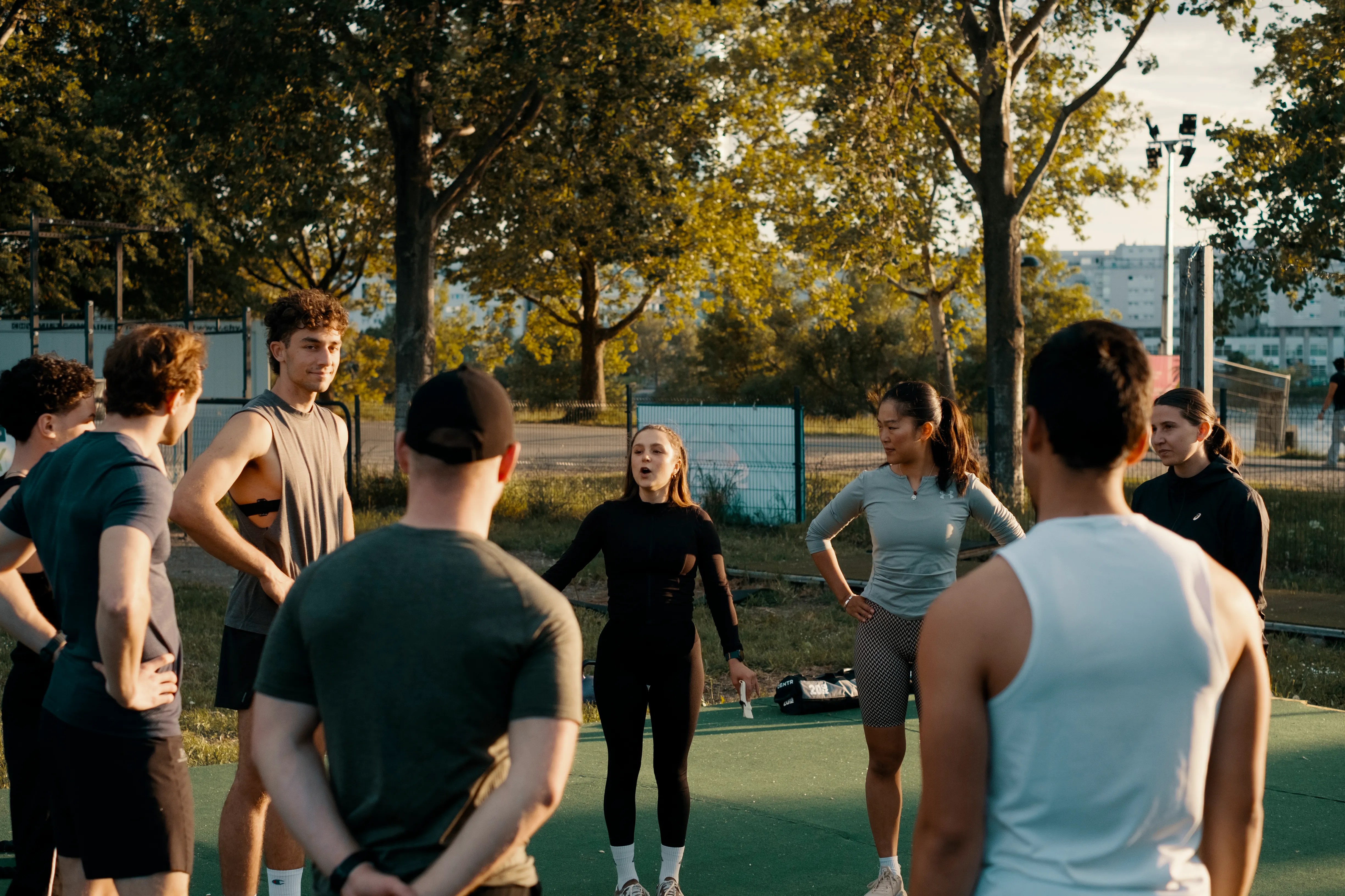 Gruppe beim Briefing auf dem Outdoor-Gym der Donauinsel, goldenes Abendlicht